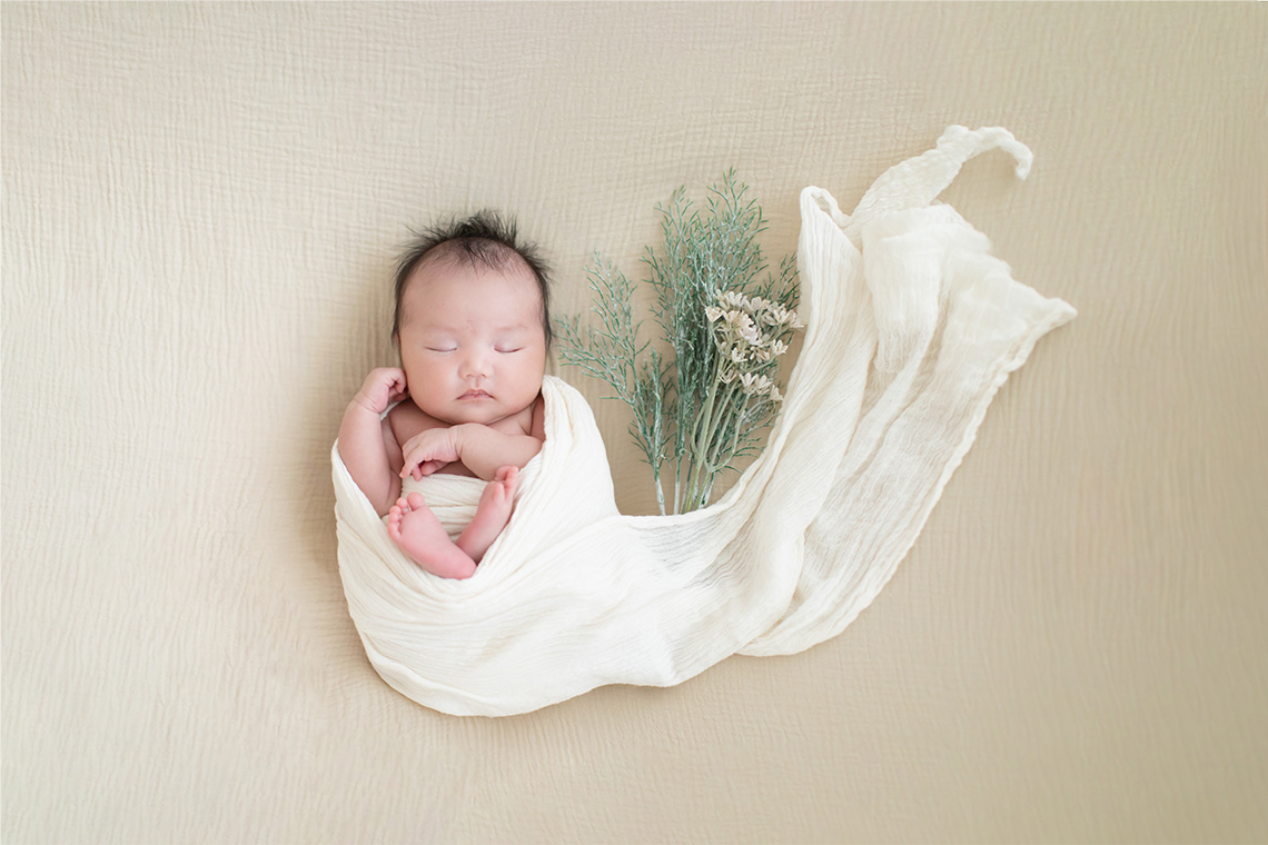 ニューボーンフォトのおくるみに包まれた赤ちゃんの写真